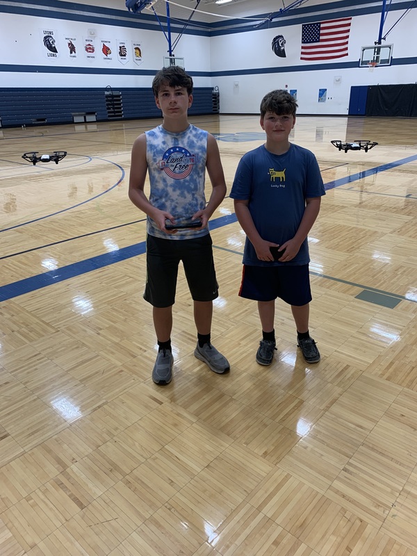 Two students flying their drones in the LMS Gymnasium